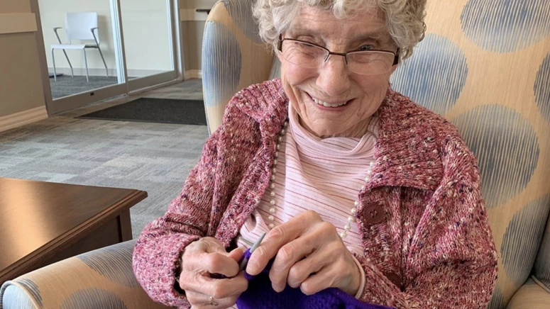 On a sofa at Hamlets Duncan retirement home, an elderly woman is knitting.