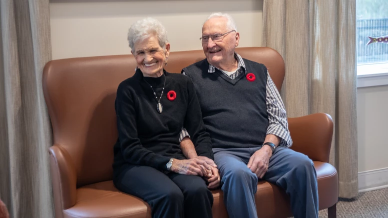 Elderly couple sitting on leather couch.