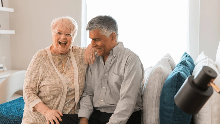 An elderly couple cuddling and laughing